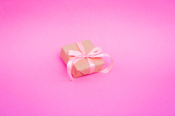 Gift wrapped in parchment, eco paper, kraft paper on a pink background.