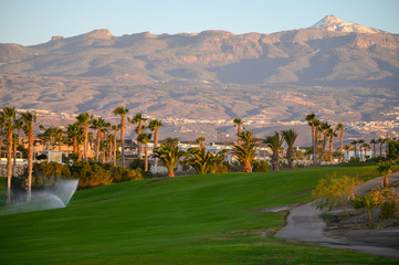 Watering on evergreen grass field on large golf course on Tenerife island, Canary, Spain