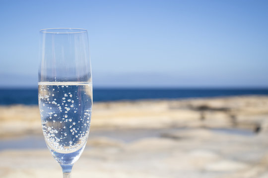 glass of bubbly champagne drinks on the beach. summer holiday background