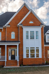 View of decorative brick covered house front double peak gable and semi circular gable window, white accent lines, paneled bay window, arch single hung window, white bump out with symmetric windows