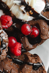 Homemade chocolate waffles with powdered sugar on a plate of raspberries with ice cream and...