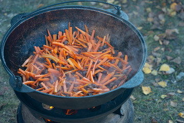 Fry sliced carrots in pilaf oil. Onions and carrots are fried in a pan in sunflower oil