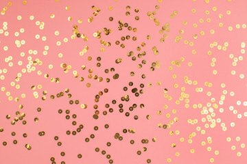 Pink pastel festive background with golden sparkling sequins. Abstract backdrop with confetti.