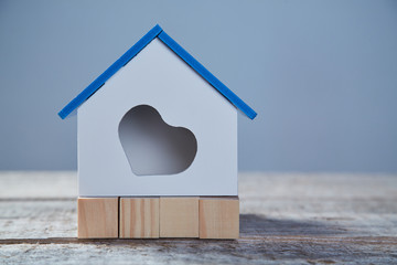 Buying and selling property. Real estate acquisition. Mortgage for starter home. Miniature of house with heart symbol on wooden surface