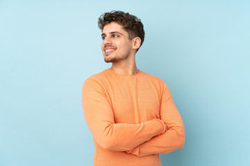 Caucasian man isolated on blue background with arms crossed and happy