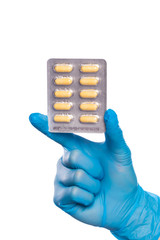 Surgeon's hand in a blue medical glove holds a blister of tablets isolated on a white background