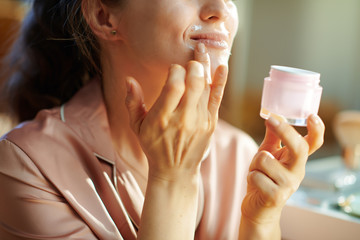 happy modern woman with cosmetic jar applying lip contour cream