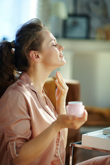 stylish woman with pink cosmetic jar applying neck cream