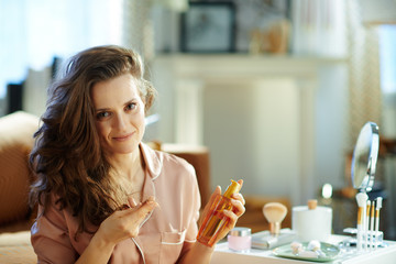 elegant woman holding hair oil bottle and checking hair ends