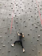 active young woman on rock wall in sport centre