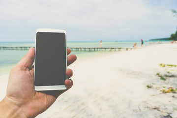 man using digital phone on the beach
