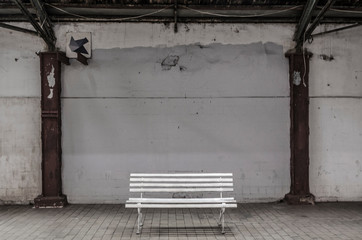 Empty bench in front of a wall.