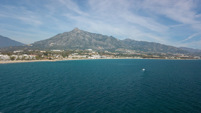 a boat navigating in from of marbella coast, malaga in the south of Spain, views of all shore in the picture of marbella town