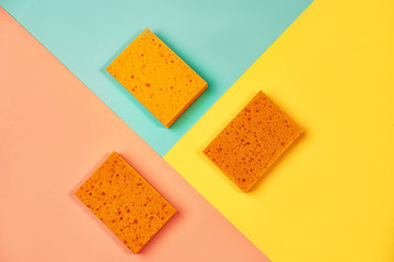 Trendy collage made of orange color sponges on yellow, pink coral and trendy mint green blue background.
