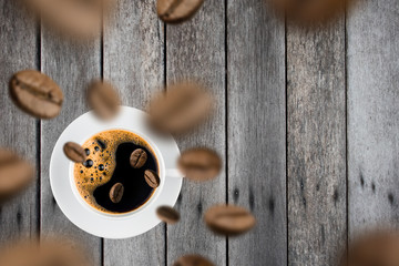 Top view of brown roasted coffee beans falling and flying to coffee cup.Represent breakfast for energy and freshness concept.