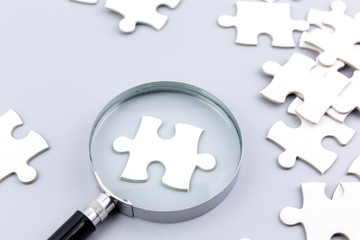 Magnifying glass to find piece of jigsaw puzzle