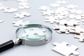 Magnifying glass to find piece of jigsaw puzzle