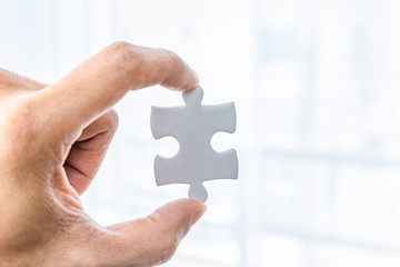 Hand holding and showing piece of jigsaw puzzle