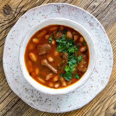 cranberry beans stew with beef chops, tomatoes, carrots, onion and garlic decorated with parsley