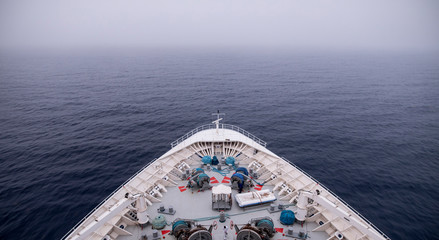 Bow of ship moving through heavy fog, with motion blur on waves.