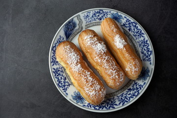 Eclairs with cream and powdered sugar on a plate