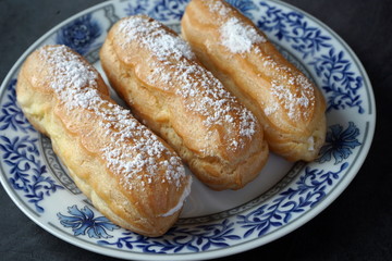 Eclairs with cream and powdered sugar on a plate
