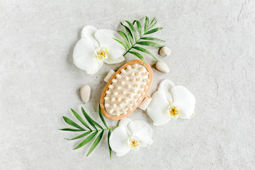Fototapeta na wymiar Spa treatment concept. Natural/Organic spa cosmetics products, massage brush and tropic palm leaves on gray marble table from above. Spa background, flat lay, top view.
