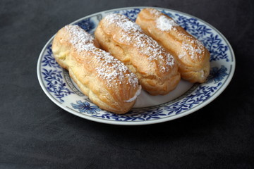 Eclairs with cream and powdered sugar on a plate
