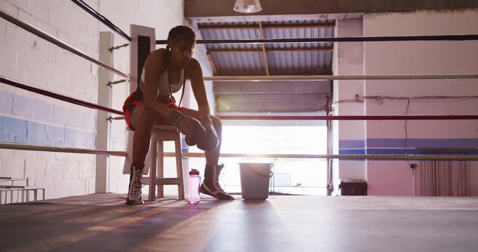 Mixed race woman resting in boxing gym