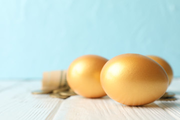 Golden eggs and money on against blue background, space for text
