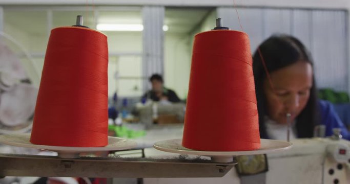 Mixed race woman using sewing machine in factory