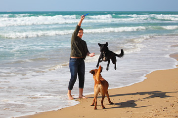 Teenage girl  playing with her dogs on the beach