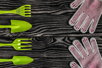 Gardening tools concept. Spade, fork, rake and gloves on black and white wooden background with...