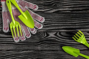 Gardening tools concept. Spade, fork, rake and gloves on black and white wooden background with...