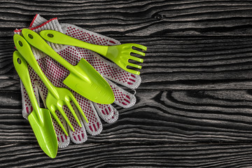 Gardening tools concept. Spade, fork, rake and gloves on black and white wooden background with...