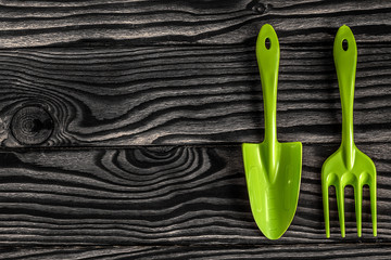 Gardening tools concept. Spade, rake and fork on black white wooden background with space for text...