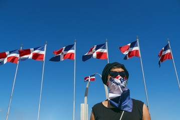 A girl with glasses, hat and scarf covering her mouth, fights for her rights with the Dominican...