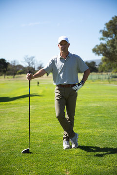 Golfer looking at camera and holding golf club