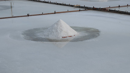 White salt gathered into a pile, surrounded by white salt, at a salt field.