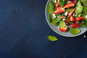 Fototapeta na wymiar Close up of a plate with strawberry salad on dark blue background