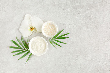 Obraz na płótnie Canvas Spa treatment concept. Natural/Organic spa cosmetics products, sea salt and tropic palm leaves on gray marble table from above. Spa background with a space for a text, flat lay, top view.