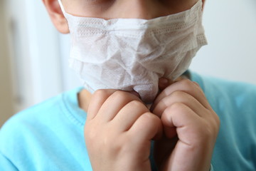 Kids wearing her mask is not comfortable, she has headache. Sick Child wearing surgical mask coughing . Kids wear health masks to prevent germs and dust . Protection against corona virus