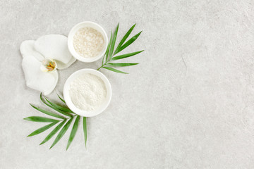 Fototapeta na wymiar Spa skincare concept. Natural/Organic spa cosmetics products, sea salt and tropic palm leaves on gray marble table from above. Spa background with a space for a text, flat lay, top view.