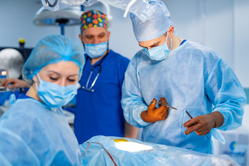 Spinal surgery. Group of surgeons in operating room with surgery equipment. Modern medical...