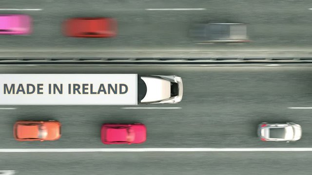 Aerial top down view of semi-trailer trucks with MADE IN IRELAND text driving along the road. Turkish business related loopable 3D animation