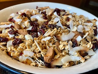 close up bowl of healthy homemade breakfast granola with coconut almonds and dried fruit