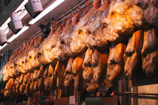 Stock photo of Iberian ham legs hanging at a market stall