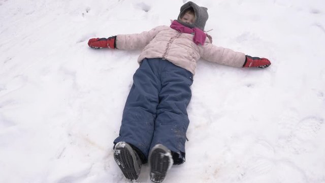 Cute Young Girl Making Snow Angel In Wintertime 