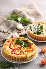 The concept of French cuisine. Quiche with peppers, tomatoes and mushrooms on a light background. Background image, copy space