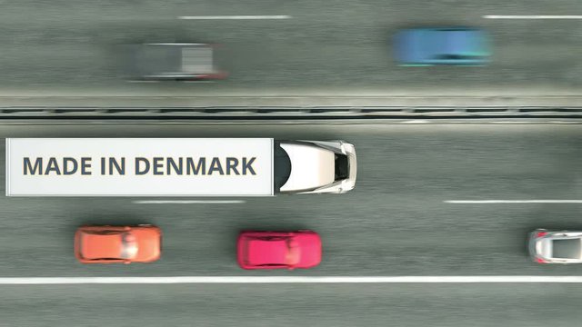 Aerial top down view of semi-trailer trucks with MADE IN DENMARK text driving along the road. Danish business related loopable 3D animation